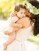 madre recoge a bebe en brazos con fondo desenfocado de arboles